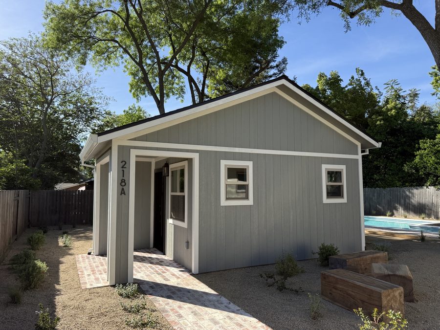 Detached backyard ADU with light siding and covered entry